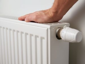 Image of a man placing his hand on a radiator.