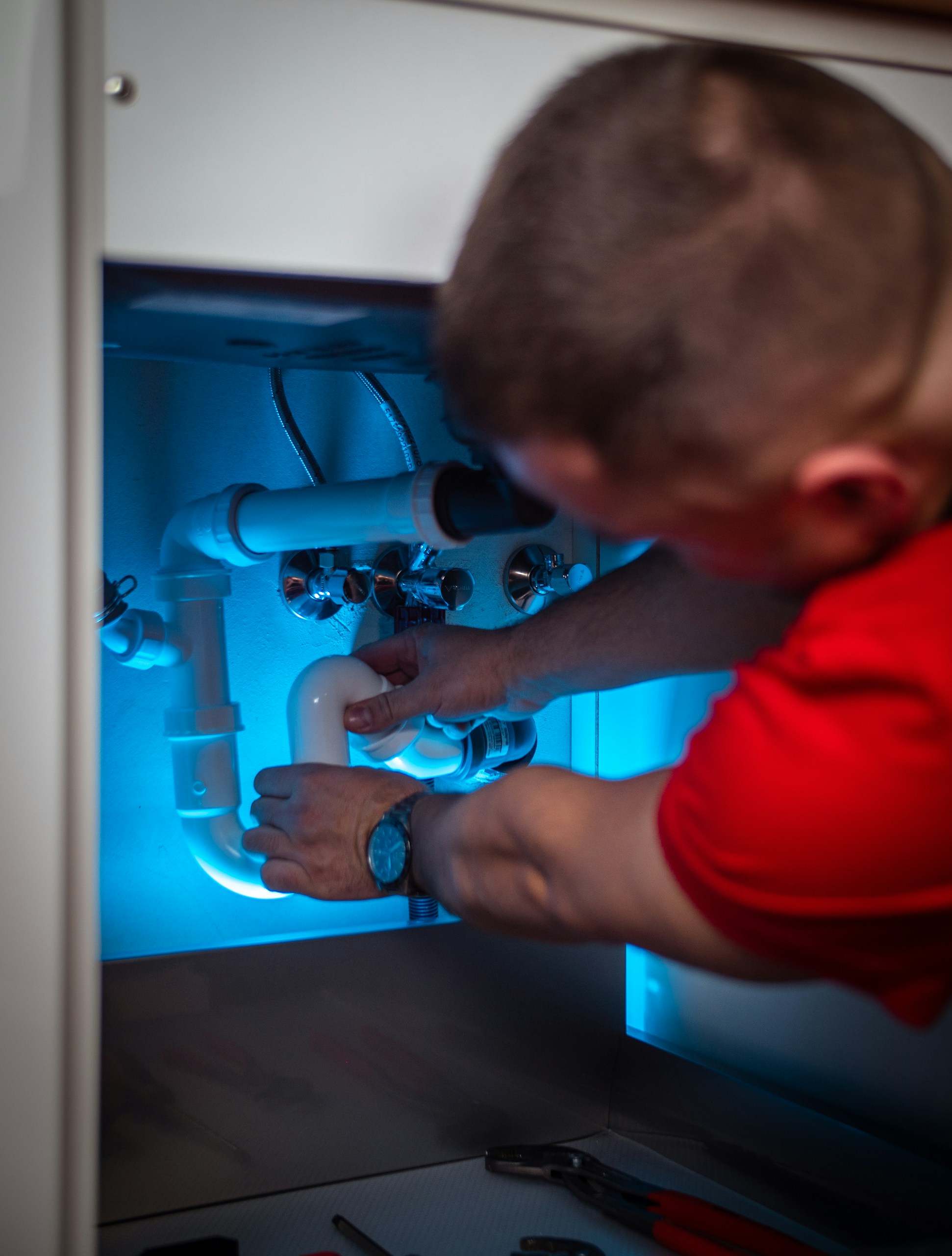 Picture of a heating engineer doing plumbing work under a sink
